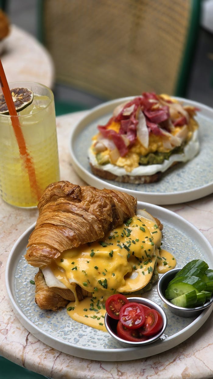 Tasty brunch dishes featuring a croissant with hollandaise and avocado toast with fresh ingredients, perfect for foodies.